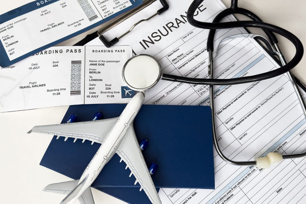 Stethoscope, plane model, boarding passes, passport, and insurance form arranged on a white surface.