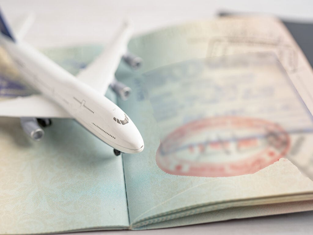 A toy airplane rests on an open passport with a visible entry visa stamp.
