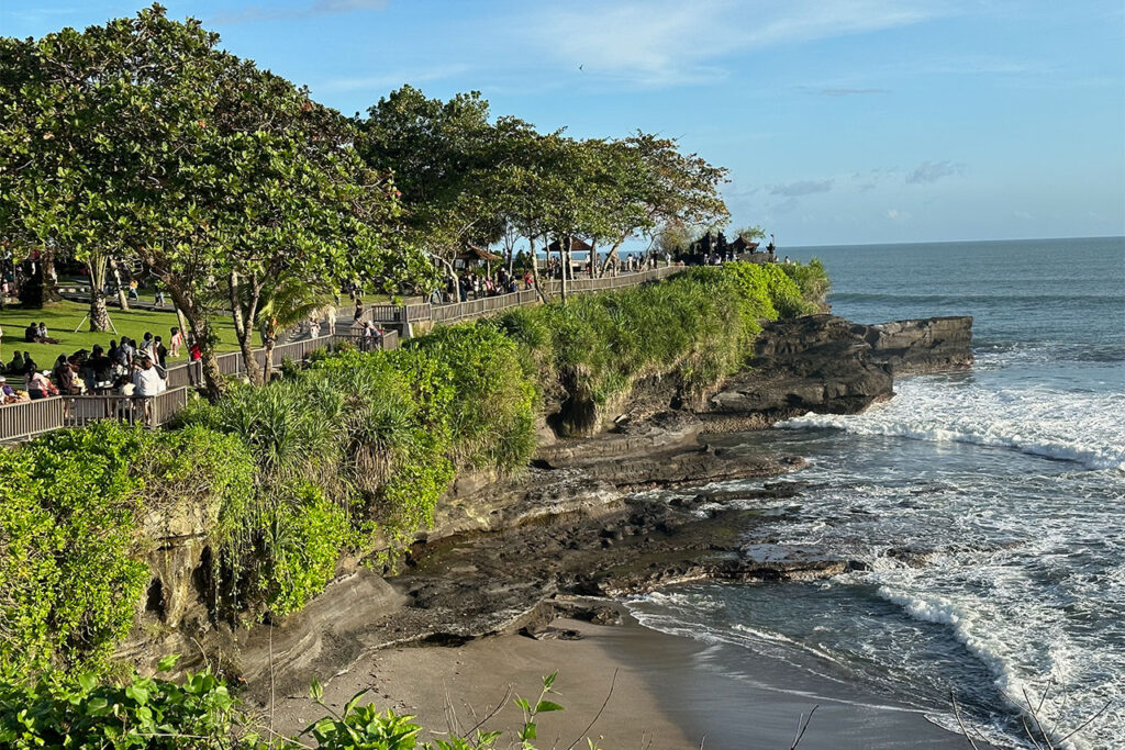 Beach cliff with lush tropical greenery, ocean waves, and visitor viewpoints at Bali Nirvana.